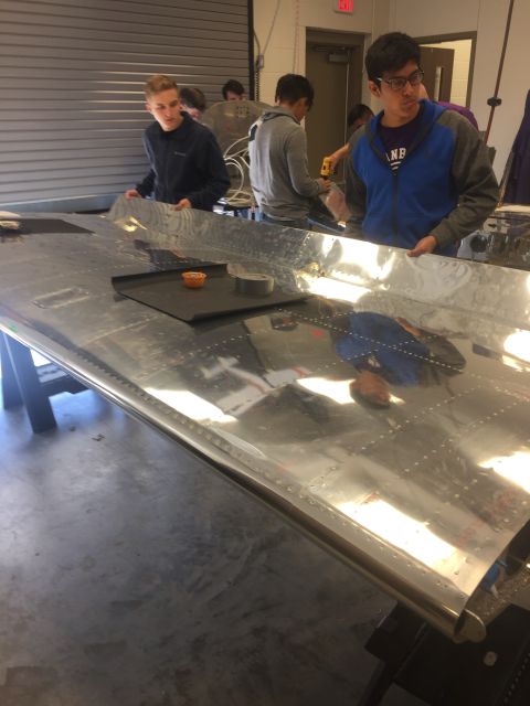 Students working on a large aircraft wing panel